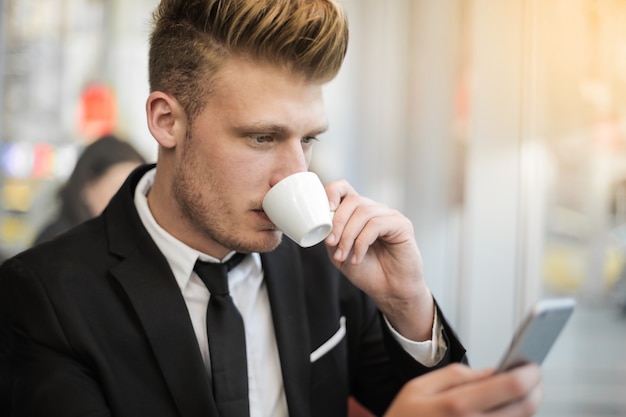 Apuesto joven empresario tomando un café