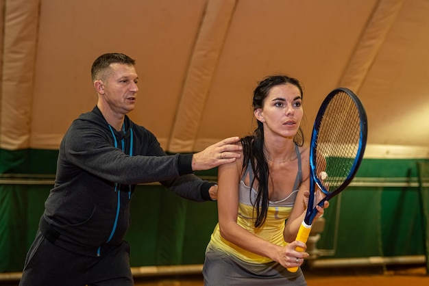 Foto apuesto joven entrenador entrena a una mujer que vino a jugar al tenis