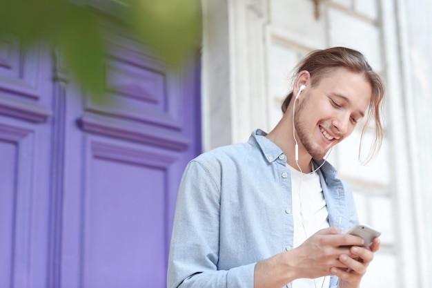 Apuesto joven escuchando música al aire libre