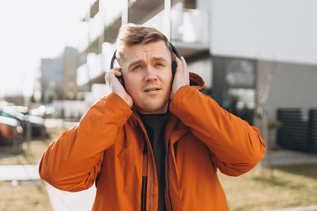 Un apuesto joven escuchando música con auriculares y de pie en la calle de la ciudad Amante de la música disfrutando de la música Concepto de estilo de vida urbano Viajero