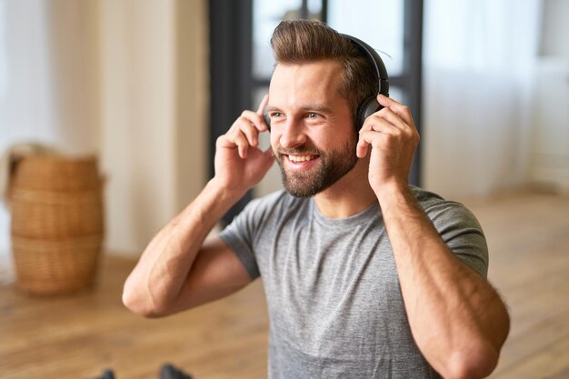 Apuesto joven escuchando música en casa