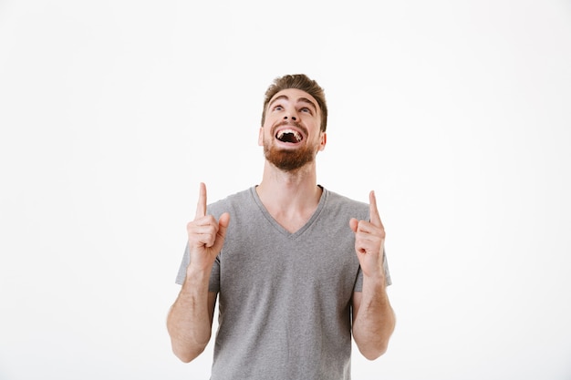 Apuesto joven feliz emocionado apuntando.