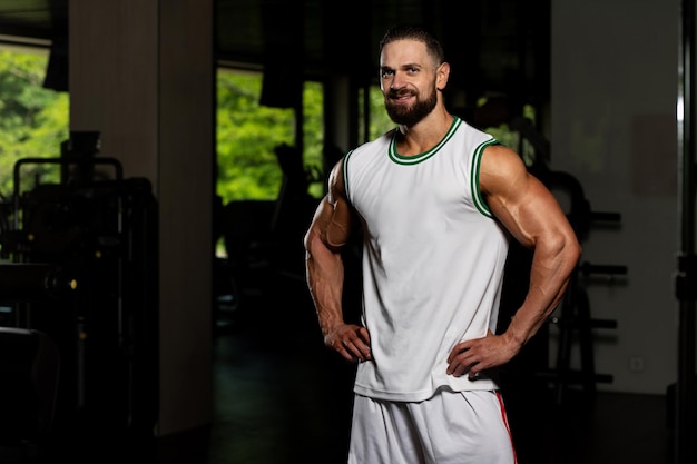 Apuesto joven guapo y atractivo con cuerpo musculoso relajante en el gimnasio