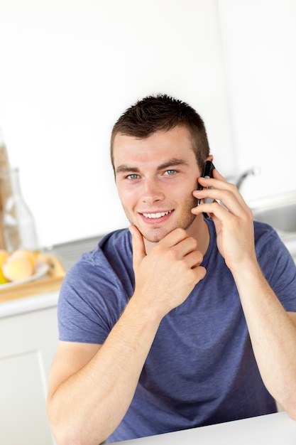 Apuesto joven hablando por teléfono y sonriendo a la cámara