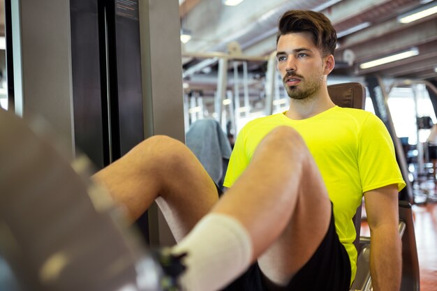 Apuesto joven haciendo ejercicio muscular en el gimnasio.