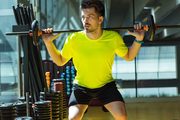 Apuesto joven haciendo ejercicio muscular en el gimnasio.