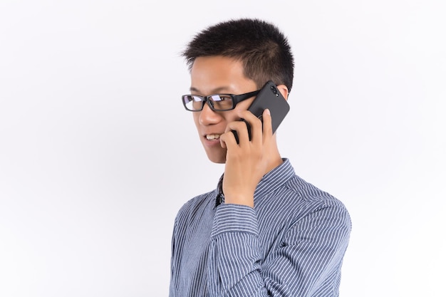 Apuesto joven haciendo una llamada telefónica aislado sobre fondo blanco.