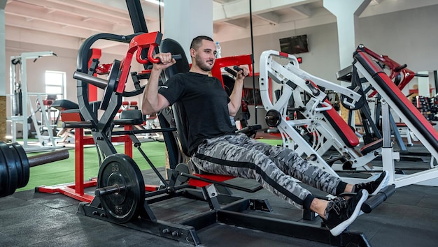 Apuesto joven con una hermosa figura trabaja como entrenador de fitness en un prestigioso gimnasio Concepto de entrenador de marido