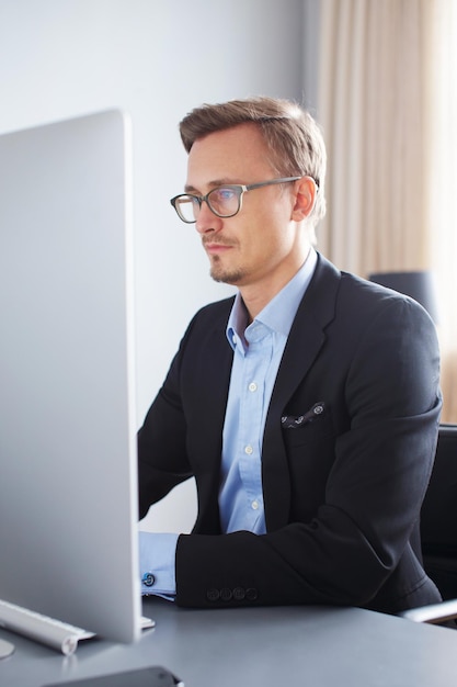 Apuesto joven hombre de negocios que trabaja con la computadora en la oficina.