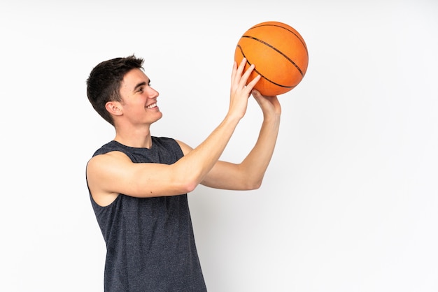 Apuesto joven jugador de baloncesto hombre sobre pared jugando baloncesto