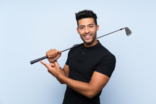 Apuesto joven jugando al golf apuntando hacia un lado para presentar un producto