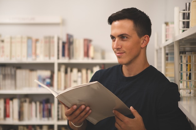 Apuesto joven leyendo en la biblioteca