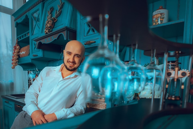 Apuesto joven listo para cocinar en la cocina de casa y sonriendo a la cámara