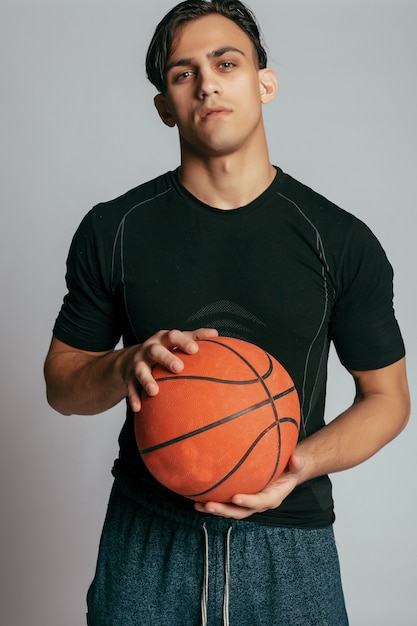 Apuesto joven llevando una pelota de baloncesto