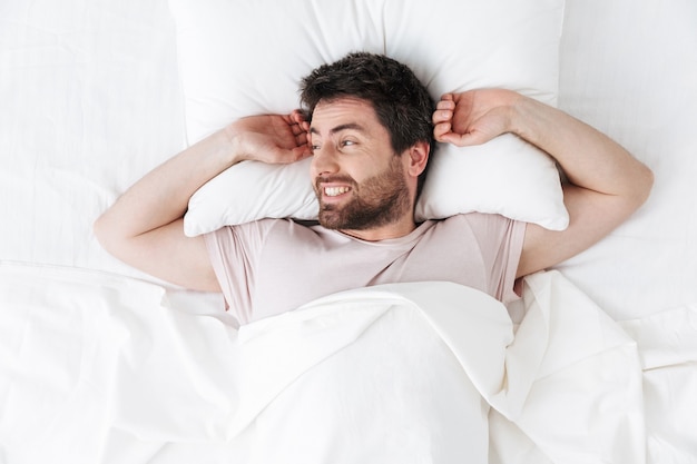 apuesto joven en la mañana estirando en la cama