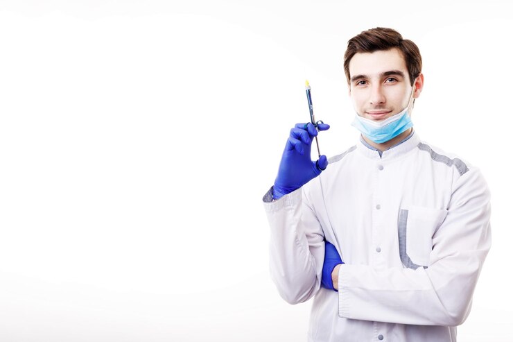 Apuesto joven médico en uniformes blancos posando con una jeringa