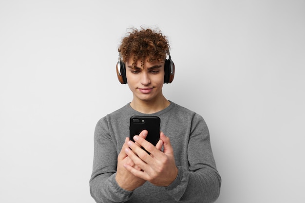 Apuesto joven mirando el teléfono auriculares moda estilo de vida inalterado