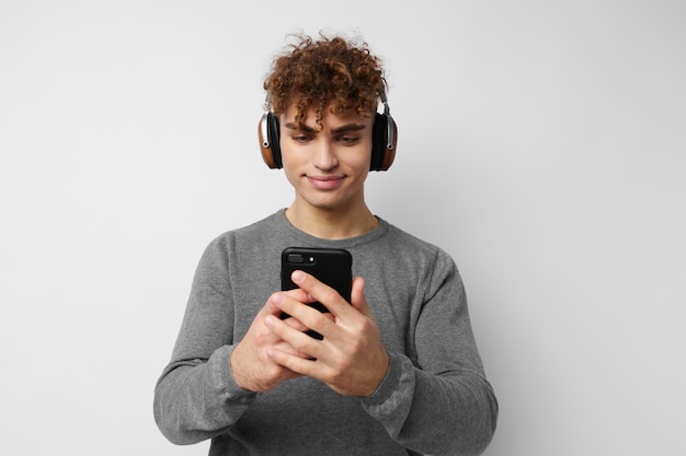 Apuesto joven mirando el teléfono auriculares moda estilo de vida inalterado