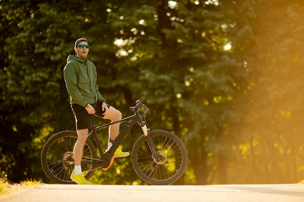 Apuesto joven montando ebike en la naturaleza