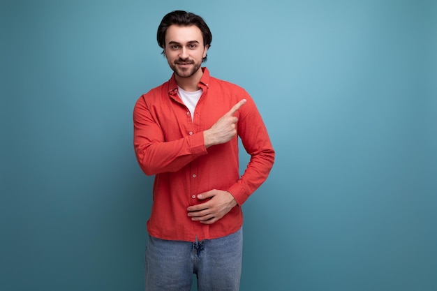 Un apuesto joven moreno con una camisa roja cuenta noticias interesantes