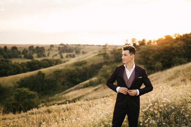 Apuesto joven novio en un traje posando en la naturaleza