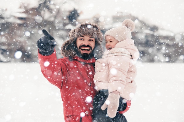 Apuesto joven papá barbudo y su pequeña y linda hija se divierten al aire libre en invierno Disfrutando de pasar tiempo juntos Concepto familiar