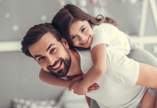 Foto apuesto joven papá y su pequeña hija linda.