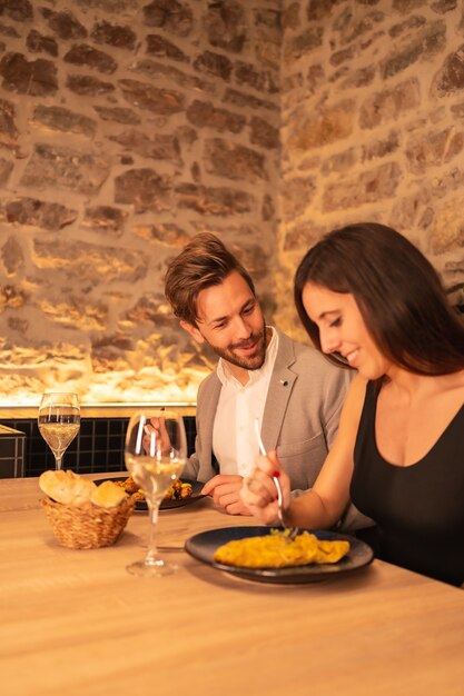 Apuesto joven pareja enamorada en un restaurante, divertirse cenando juntos, celebrando el Día de San Valentín