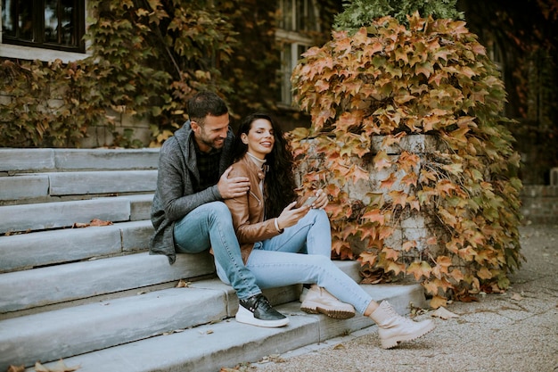 Apuesto joven pareja sentada en las escaleras al aire libre en un día de otoño