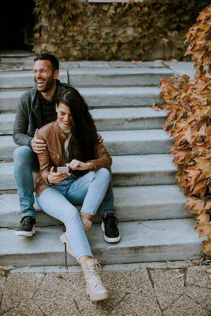 Apuesto joven pareja sentada en las escaleras al aire libre en un día de otoño