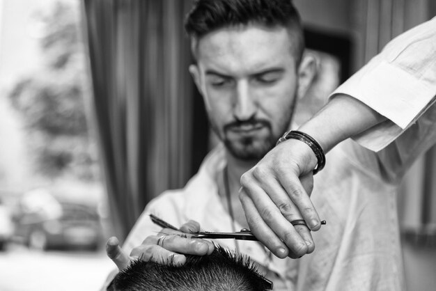 Apuesto joven peluquero dando un nuevo corte de pelo al cliente masculino en el salón