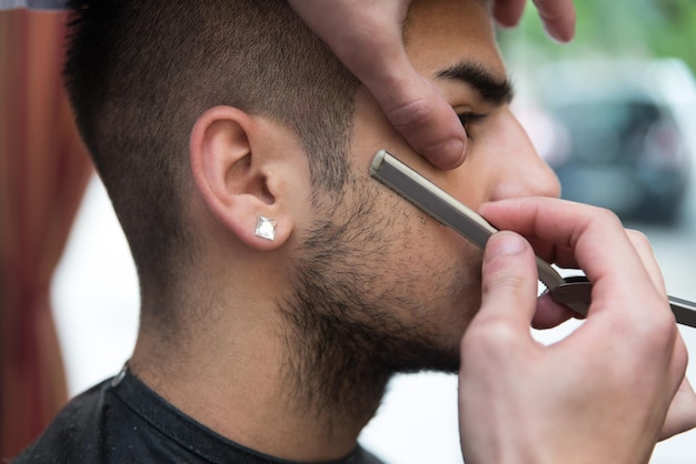 Apuesto joven peluquero dando un nuevo corte de pelo al cliente masculino en el salón