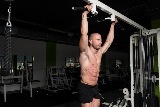 Apuesto joven de pie fuerte en el gimnasio y flexionando los músculos Muscular culturista atlético Modelo de fitness posando después de los ejercicios