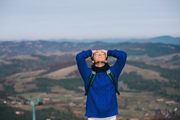 Apuesto joven de pie sobre una roca, disfrutando de la vista