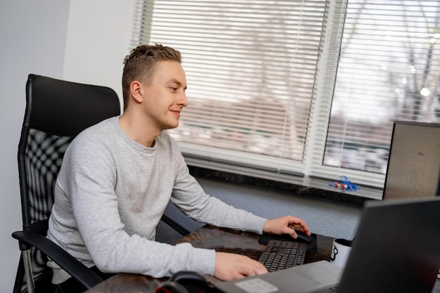 Apuesto joven programador que trabaja en la oficina con emociones de placer Desarrollando el concepto de tecnologías de programación y codificación