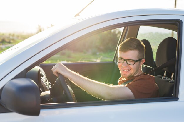 Apuesto joven riendo feliz conduce un coche.