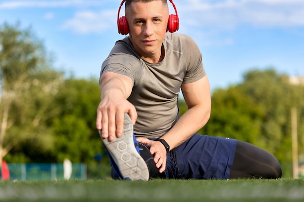 Apuesto joven en ropa deportiva se estira calentándose en la calle