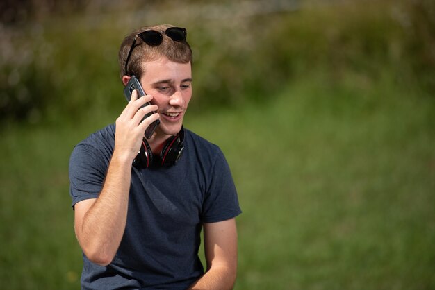 Apuesto joven rubio hablando por teléfono al aire libre Retrato con espacio de copia verde