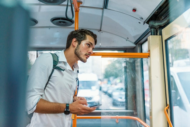 Foto apuesto joven con smartphone en autobús