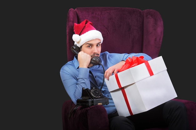 Apuesto joven con sombrero rojo de Papá Noel hablando por teléfono