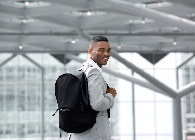 Apuesto joven sonriendo con bolsa en el aeropuerto