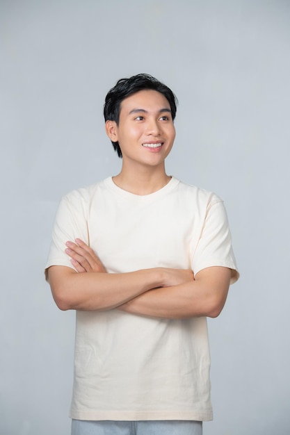 Apuesto joven sonriendo con los brazos cruzados sobre fondo blanco.