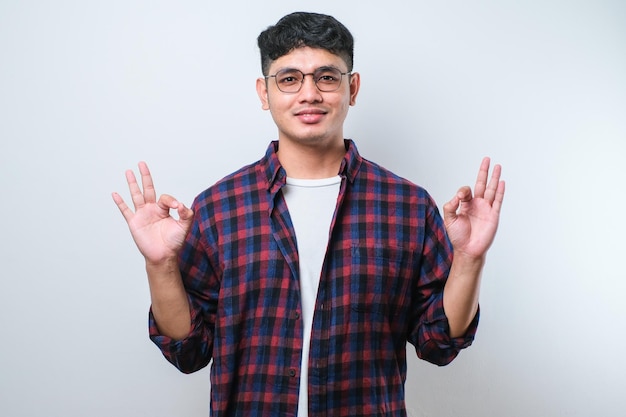 Apuesto joven sonriendo positivamente haciendo bien el signo con la mano y los dedos expresión exitosa