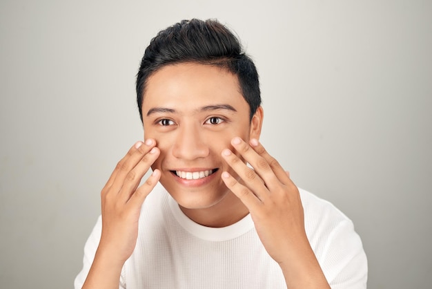 Apuesto joven sonriente tocándose la mejilla