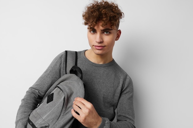 Apuesto joven en un suéter gris mochila moda fondo aislado