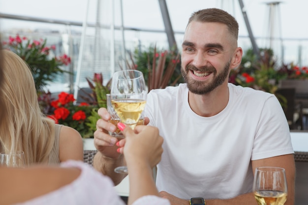 Apuesto joven tintineo de vasos con su novia durante una cita en el restaurante de la azotea