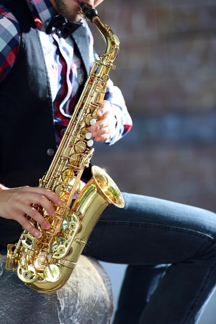 Foto apuesto joven toca el saxofón al aire libre de cerca