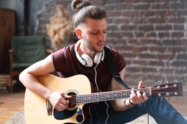 Apuesto joven tocando la guitarra acústica