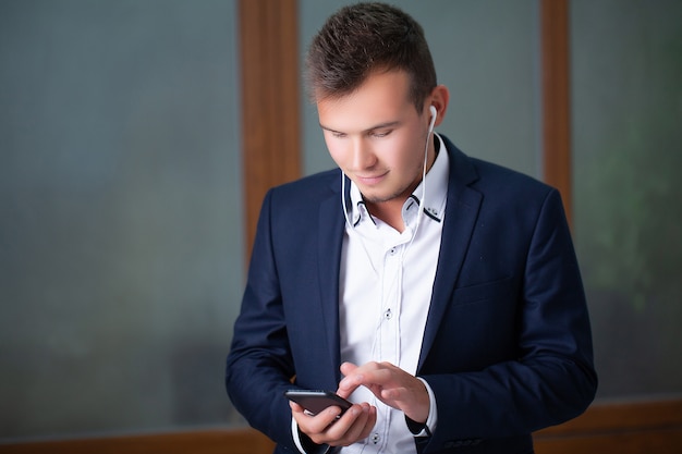 Apuesto joven trabajador utiliza un teléfono en la oficina de la empresa