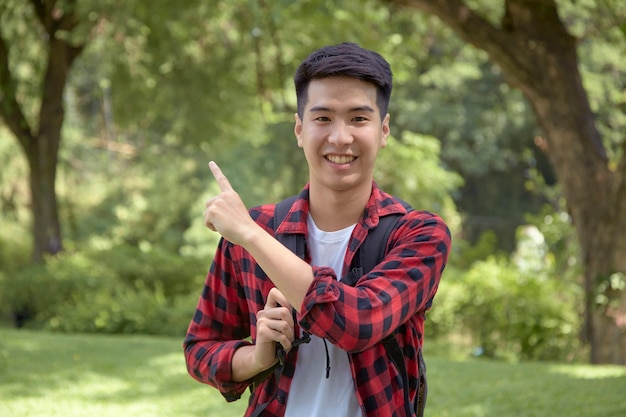 Un apuesto joven turista feliz llevando una mochila en el bosque verde